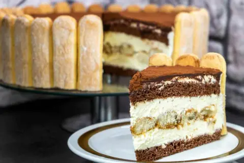 Ein köstliches Stück Tiramisu Torte mit Löffelbiskuits und Kakao bestäubt.