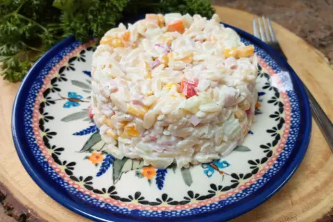 Pyszna sałatka z makaronem orzo, szynką i ogórkiem, podana na ozdobnym talerzu.