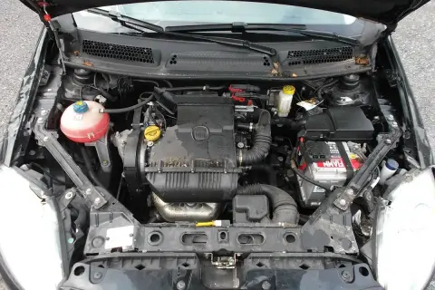 Silnik w fiat bravo 2011, widok z góry. Widać akumulator, zbiornik płynu chłodniczego i elementy silnika.