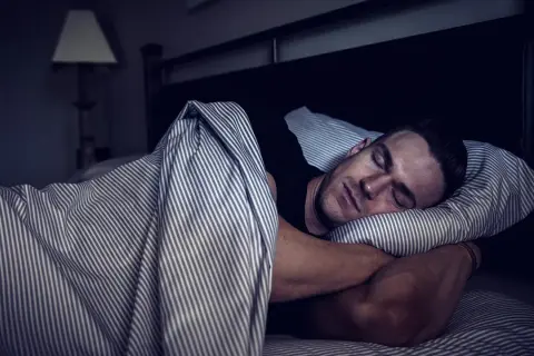 Man sleeping soundly, embracing deep sleep for optimal muscle recovery.