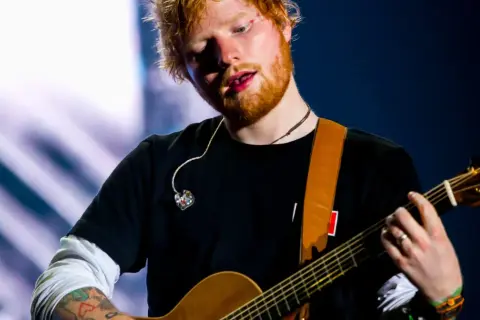 Ed Sheeran gra na gitarze akustycznej na scenie.