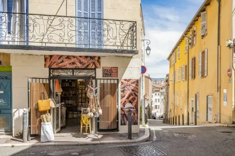 Bunte Häuser und ein Gewürzladen in der **Marseille Altstadt**. Eine schmale Gasse führt bergauf, gesäumt von sonnengelbem Mauerwerk und blauen Fensterläden.