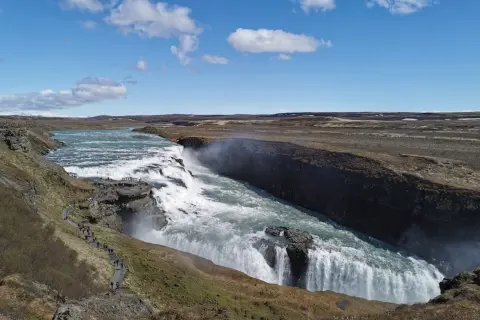 Potężny wodospad Gullfoss, część islandzkiego Złotego Kręgu, z turystami na ścieżce widokowej.