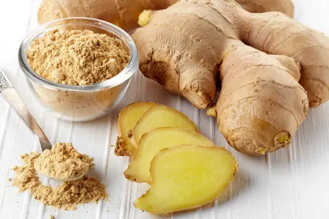 Frische Ingwerwurzeln, Scheiben und Pulver in einer Schale. Getrockneter Ingwer gesund und vielseitig einsetzbar.