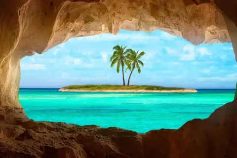 Vista da una grotta su un'isola con palme e un mare cristallino, il mare più bello del mondo.