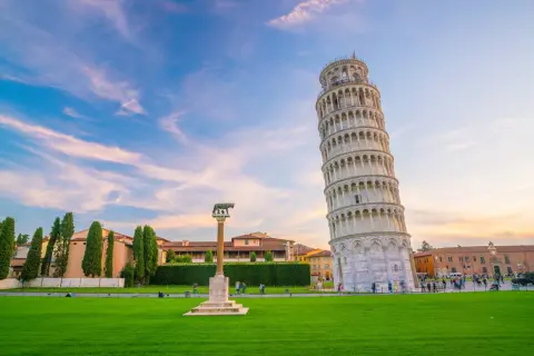 La Torre di Pisa, con il suo fascino inclinato, è al centro di una ricerca visiva, circondata da un prato verde e un cielo al tramonto.