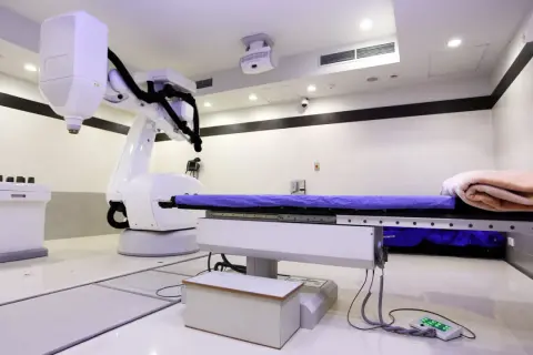 Ein CyberKnife-Behandlungsraum mit Roboterarm und Liege. Mögliche CyberKnife Nachteile sind die Kosten und die Notwendigkeit präziser Planung.