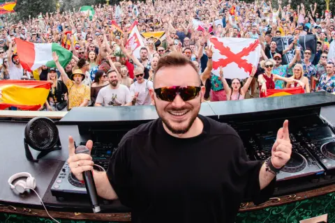 DJ Skytech rozkręca tłum na festiwalu, wśród flag Hiszpanii i Włoch.