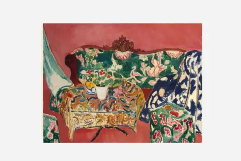 A vibrant interior scene by Matisse, capturing the joy of life with a floral sofa, patterned tablecloth, and a vase of flowers.