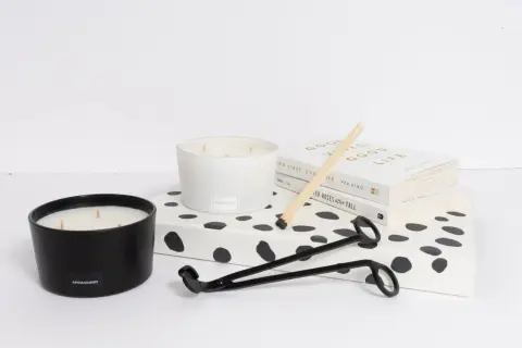 Candle care essentials: two candles, a wick trimmer, matches, and books. Learn how to remove candle wax for a cleaner burn.
