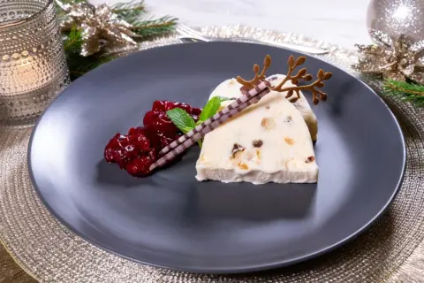 Ein festlicher weihnachts nachtisch: Eisparfait mit Beerenkompott, Schokoladenstäbchen und Rentiergeweih-Dekoration.