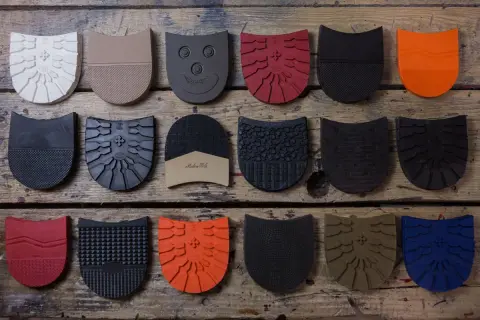 Różnobarwne fleki do butów o różnych wzorach i fakturach ułożone na drewnianym tle.