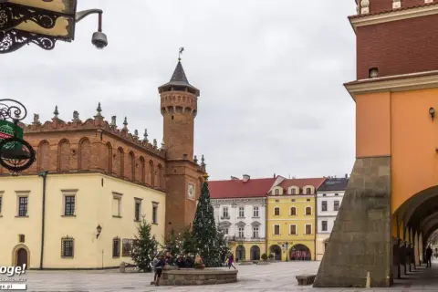 Rynek w Tarnowie zimową porą. W centralnym punkcie placu stoi choinka, a w tle widać zabytkowe kamienice i wieżę ratuszową.