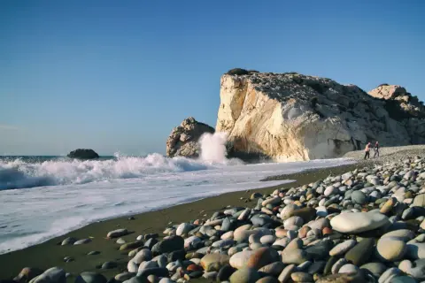 Skała Afrodyty, gdzie fale rozbijają się o brzeg, a kamienista plaża wita spacerowiczów.