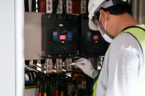 Tekniker markerar anslutningar vid jordfelsbrytare installation. Säkerhet först vid elarbeten.