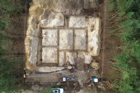 Budowa fundamentów domu w lesie. Widać zbrojenie i szalunki. To etap prac poprzedzający badania geotechniczne gruntu.