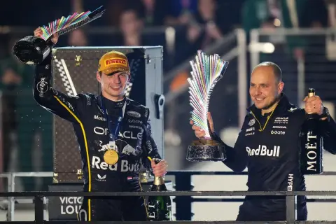 Max Verstappen celebra con un trofeo y champán, junto a Gianpiero Lambiase, tras una victoria.