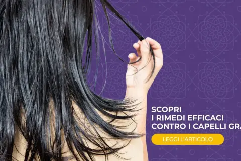 Capelli lunghi e scuri, che sembrano un po' appesantiti, con una mano che ne raccoglie una ciocca. Scopri rimedi efficaci contro i capelli grassi.