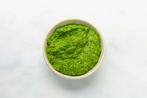 Eine Schüssel mit leuchtend grüner Salsa verde, die frisch und würzig aussieht.
