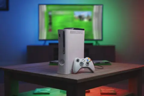 Biały Xbox 360 z kontrolerem na stoliku, przypominający czasy, kiedy wyszedł.