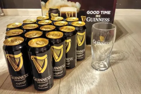 Dużo puszek piwa Guinness i szklanka, gotowe na dobrą zabawę.