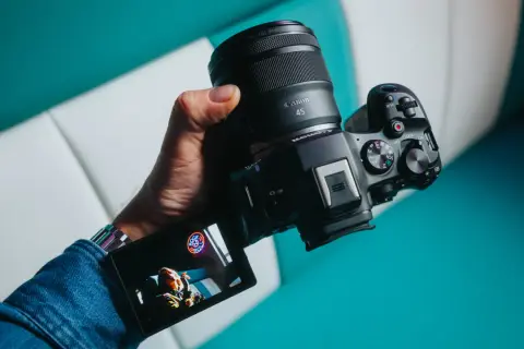 Dłoń trzyma aparat Canon z obiektywem RF 45mm. Wyświetlacz pokazuje zdjęcie.