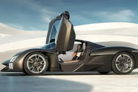 Ciemnobrązowy hypercar z otwartymi drzwiami, siedzeniami w kolorze karmelu, na tle pustynnego krajobrazu.