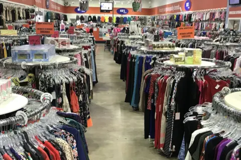 Pasillos llenos de ropa en una tienda, ideal para aprender como montar una tienda de ropa de segunda mano.