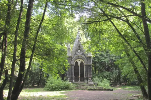 Un piccolo tempietto gotico nel **bosco delle fate a Torre Alfina**, circondato da alberi rigogliosi e sentieri ombrosi.