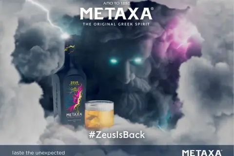 Metaxa 12 cena. Zeus powraca! Butelka Metaxy Zeus Edition i szklanka z bursztynowym trunkiem na tle burzy i twarzy Zeusa.