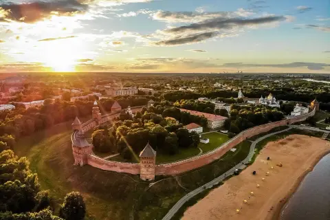 Solnedgång över Novgorod, en historisk stad med en imponerande kreml. Denna vy liknar en gammal **Novgorod karta** med sina befästningar och gyllene kupoler.