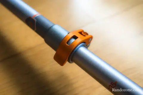Gros plan sur le mécanisme de serrage orange d'un bâton de marche pliable ou télescopique, prêt pour l'aventure.