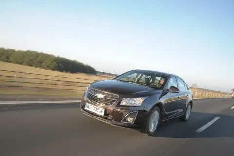 Brązowy Chevrolet Cruze 1.8 benzyna jedzie autostradą.
