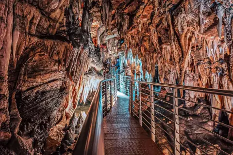 Sentiero illuminato tra stalattiti e stalagmiti nelle grotte in Toscana. Un viaggio sotterraneo tra formazioni rocciose millenarie.