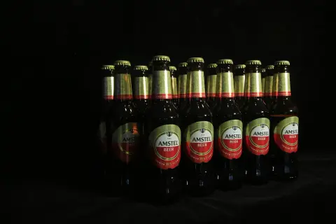 Rząd butelek piwa Amstel na czarnym tle. Czy piwo jest niezdrowe? To zależy od ilości.