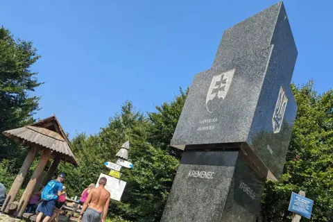 Trójstyk granic Bieszczady: monumentalny obelisk z herbami Słowacji i Ukrainy, otoczony zielenią.