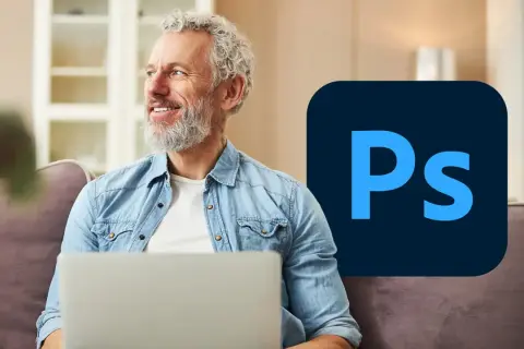 Uśmiechnięty mężczyzna z laptopem i logo Photoshopa.