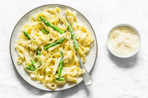 Pyszny makaron ze szparagami w sosie śmietanowym, posypany parmezanem. Idealny na lekki obiad.