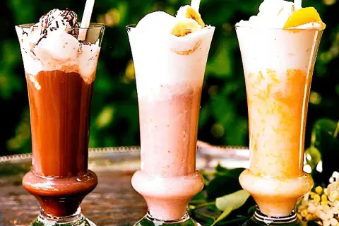 Tre läckra milkshakes i glas med grädde och strössel. Perfekt för ett somrigt milkshake recept!