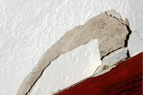 Odkruszający się tynk wewnętrzny, odsłaniający beton. Dowiedz się, jak naprawić odpadający tynk wewnętrzny.
