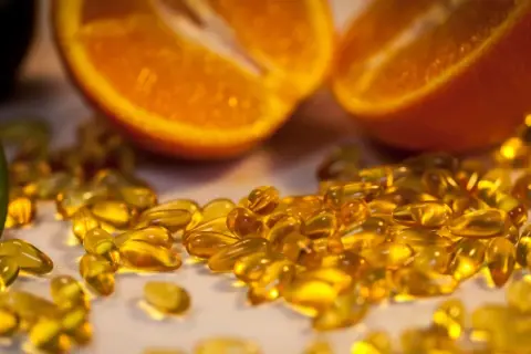Orangenscheiben und Kiwi neben vielen gelben Kapseln. Die Wirkung von hochdosiertem Vitamin C für die Gesundheit.
