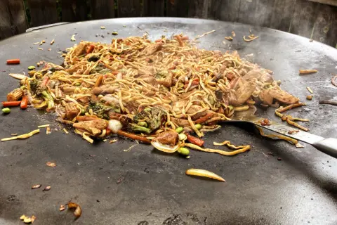 En wok med nudlar, kyckling och grönsaker tillagas på en muurikka. Ett perfekt recept för en muurikka wok!