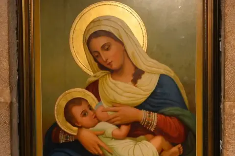 Virgen María amamantando al Niño Jesús, con halos dorados y vestimentas tradicionales.