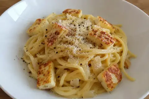 En krämig vegetarisk carbonara med spaghetti, stekt halloumi och rikligt med parmesanost och svartpeppar.