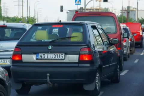Korek uliczny, gdzie widać samochody z indywidualnymi tablicami rejestracyjnymi, np. "WO LUXUS".