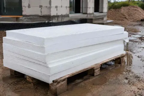 Stos białych płyt styropianowych na palecie, gotowych do układania pod wylewkę. Unikaj błędów przy izolacji!