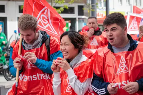 Junge Leute in roten Westen mit IG Metall Logo bei einer Demonstration. Sie wirken engagiert und hoffnungsvoll für die jav Wahlen.