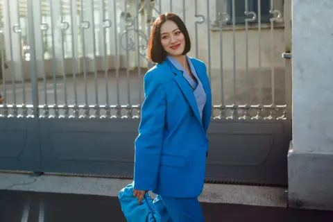Donna con tailleur blu elettrico, borsa coordinata. Quali scarpe abbinare per un look audace?