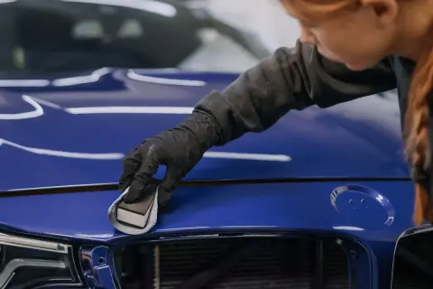 Rękawiczka z gąbką aplikuje produkt na niebieski lakier, by usunąć drobne odpryski na lakierze i nadać mu blask.