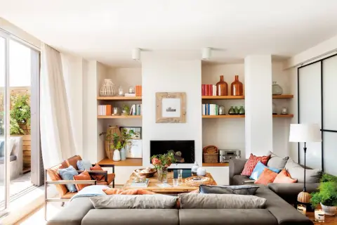 Ideas para un salón comedor acogedor con sofás grises, sillones de cuero, chimenea y estanterías llenas de libros y objetos decorativos.